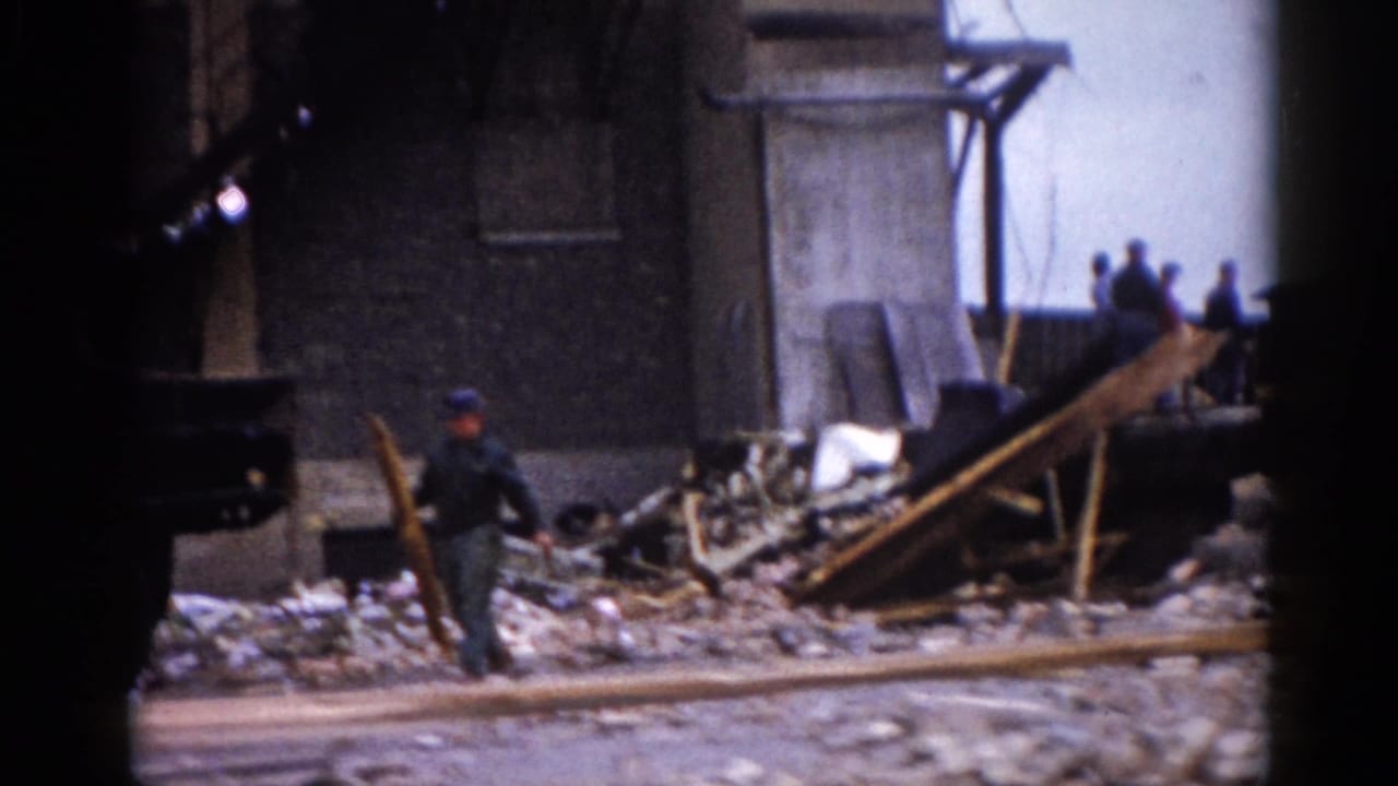Uniformed official moves through timber and brick rubble at a damaged building site, filmed on 8mm in what may be Illinois, circa 1962.