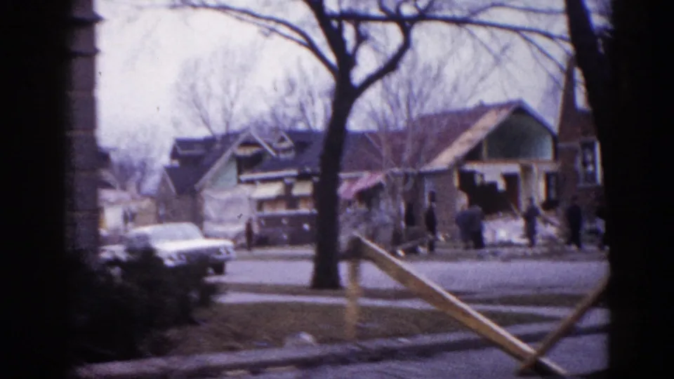 Illinois neighborhood street circa 1962 with residential houses showing apparent construction or demolition, bare trees, period automobiles, and lumber framing visible in the foreground.