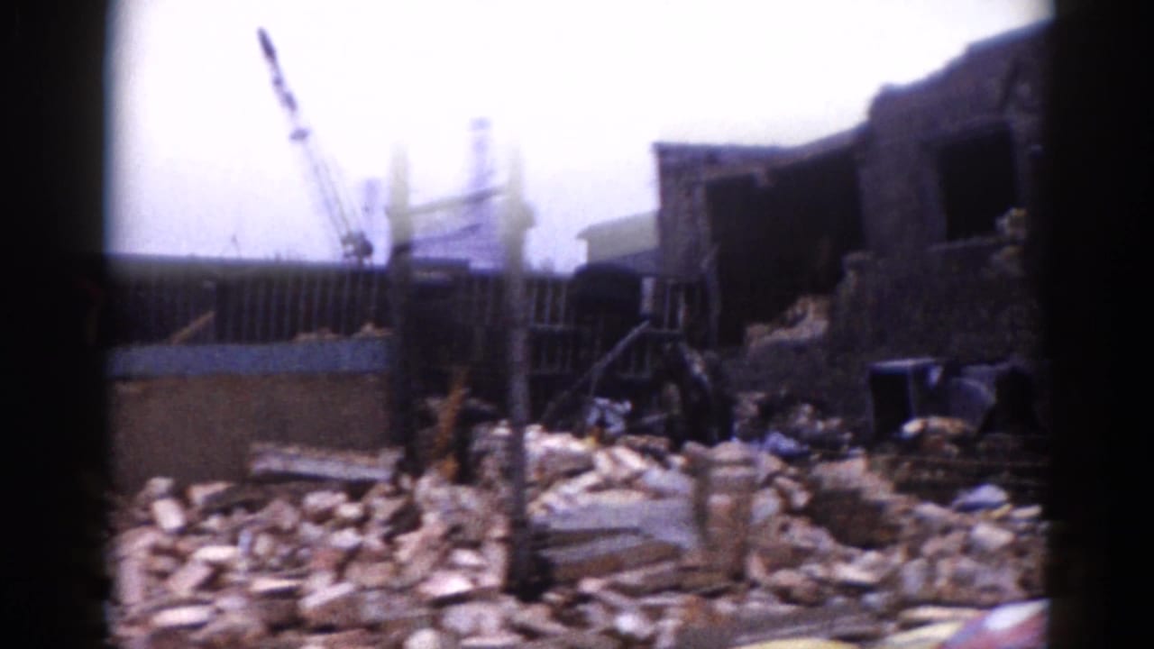 8mm color footage, c.1962, Illinois: extensive brick rubble from a collapsed industrial building with a construction crane and partial walls in the background.