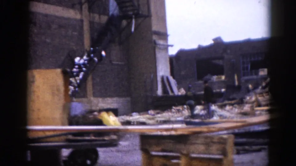 8mm color footage, c.1962, Illinois: standing brick column amid rubble and scattered timber with what appears to be yellow machinery or equipment at ground level.