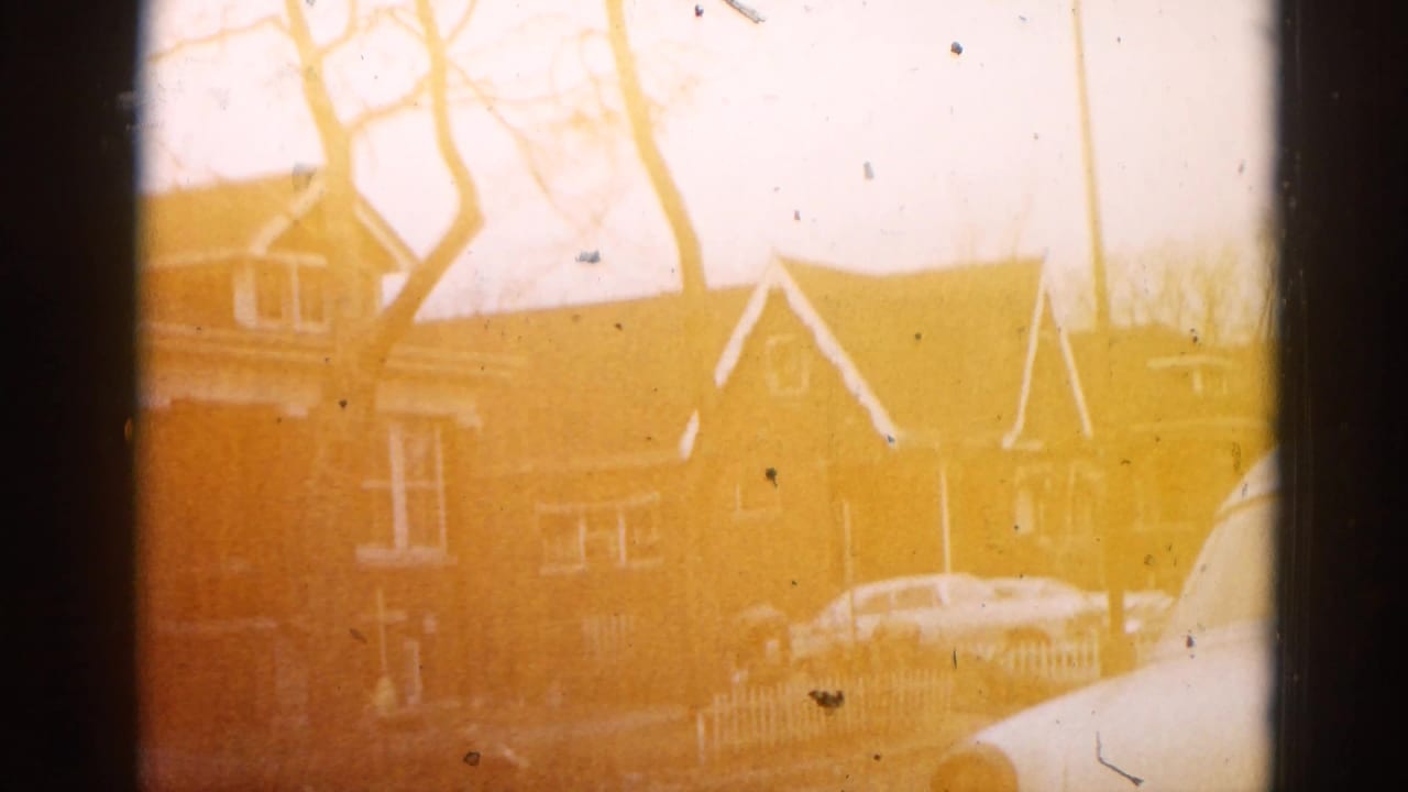 Brick house with gabled roof and bare winter trees under a heavy amber-orange 8mm color cast.