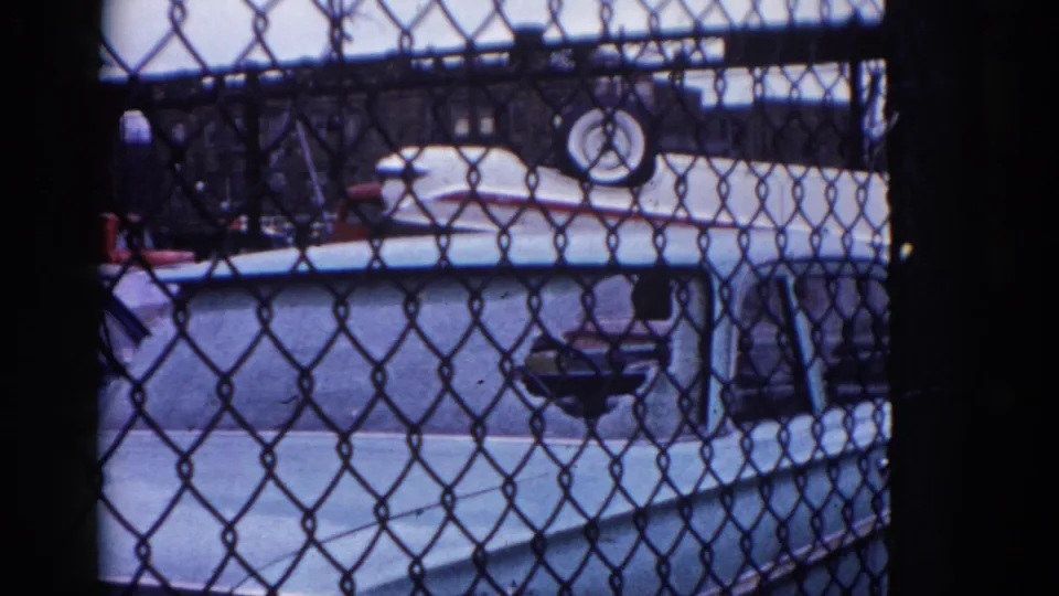 8mm film, circa 1962, Illinois: final frame with red car shifted to right, light blue car body prominent through chain-link fence, inverted white car still visible above