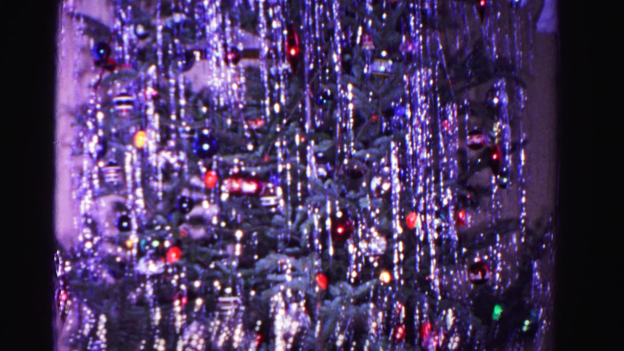 Close-up of a Christmas tree densely covered in silver tinsel with red and blue glass ball ornaments.