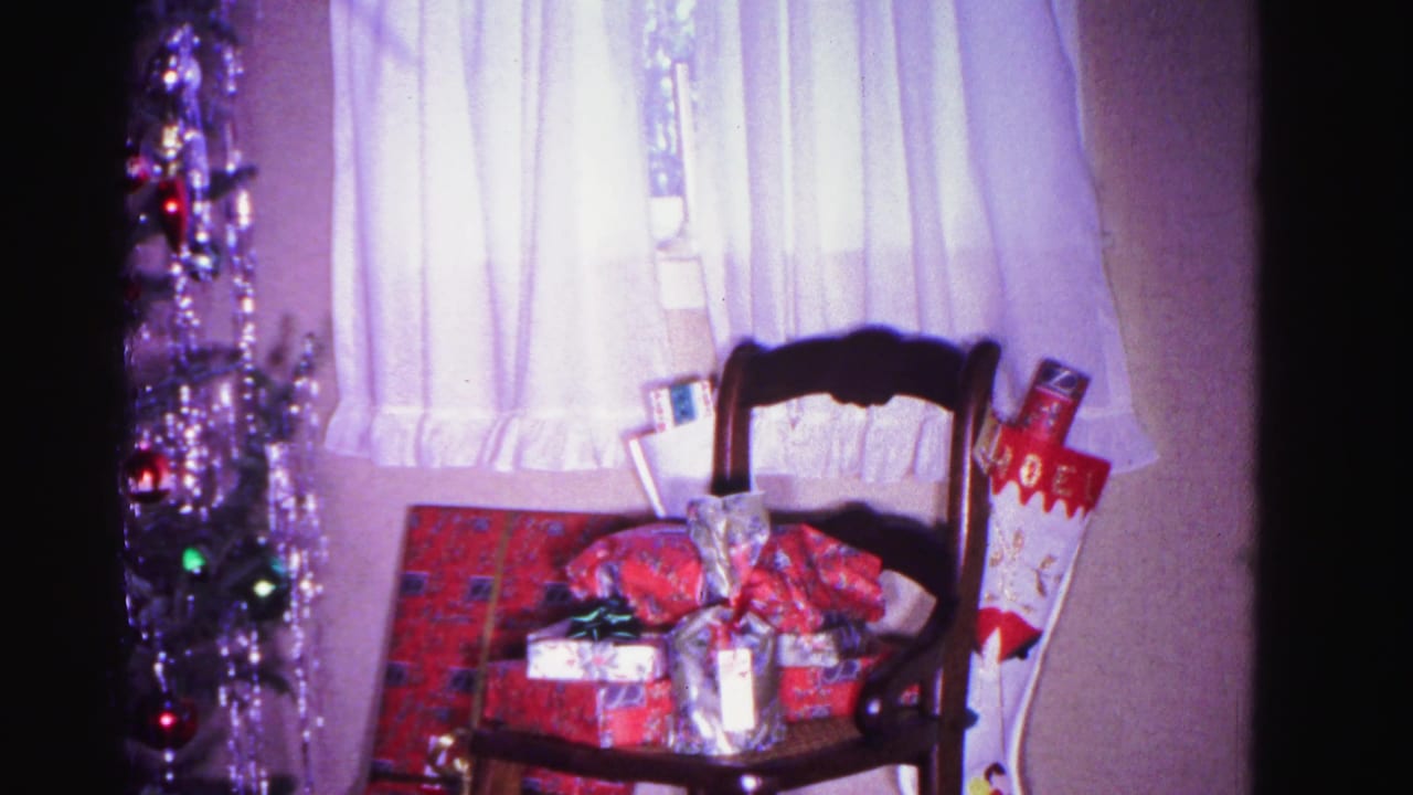 Wooden chair stacked with wrapped presents next to a densely tinsel-draped Christmas tree, Hagerstown, Maryland home interior, circa 1962, 8mm.