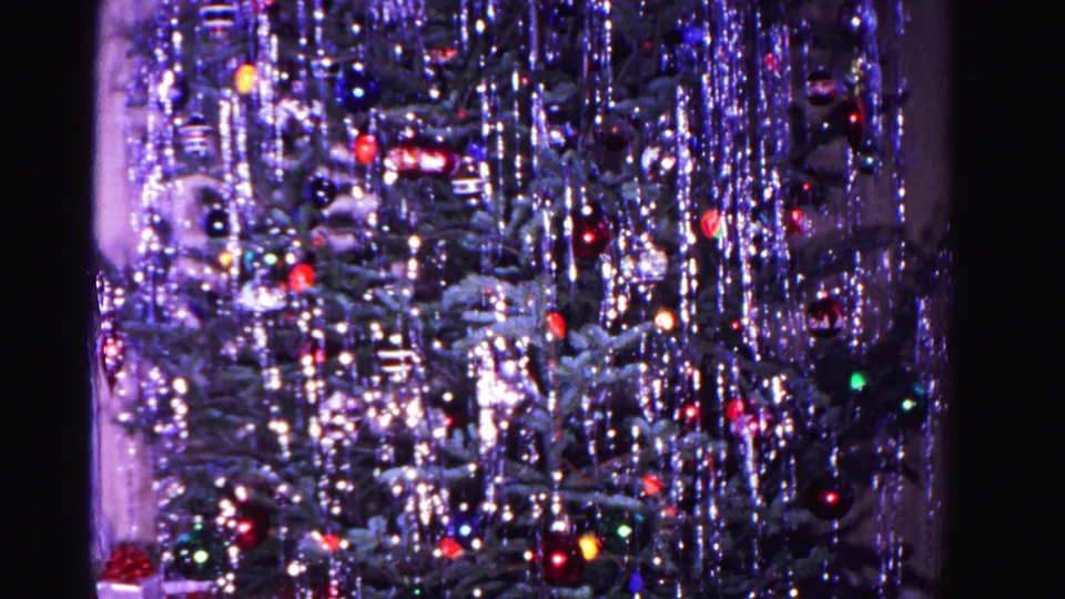 Christmas tree draped in dense silver tinsel with red, green, and blue ornaments visible through the branches, circa 1962, 8mm.