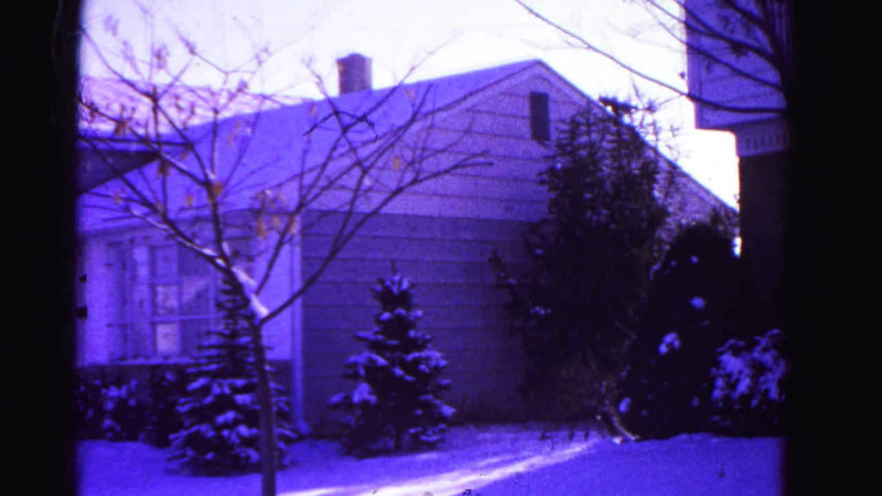 Second exterior shot of the same snow-covered suburban home in Hagerstown, Maryland, circa 1962, on aged 8mm film with purple dye shift.