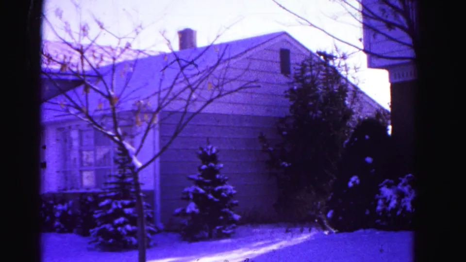 Second exterior shot of the same snow-covered suburban home in Hagerstown, Maryland, circa 1962, on aged 8mm film with purple dye shift.