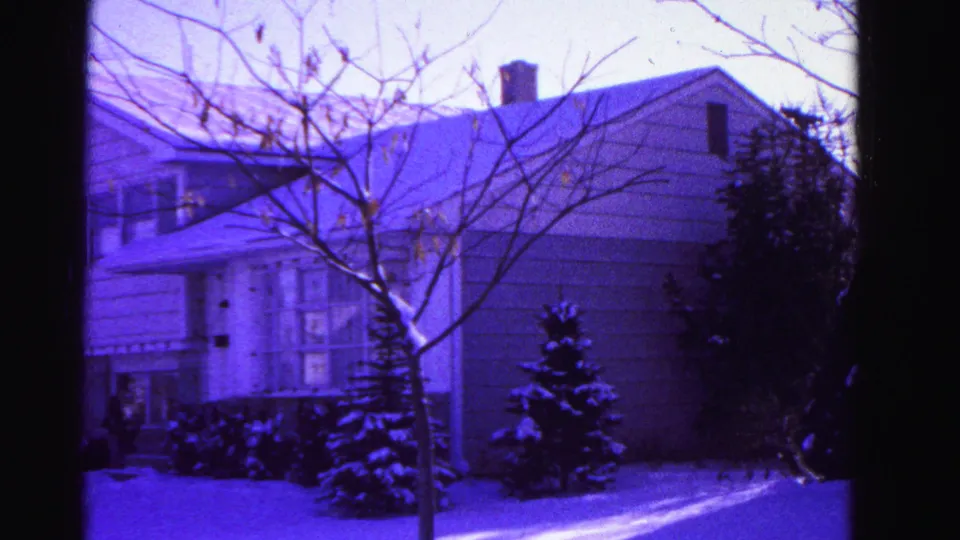 Third exterior view of a snow-covered suburban residence in Hagerstown, Maryland, circa 1962, with bare trees prominent and strong purple film dye cast.