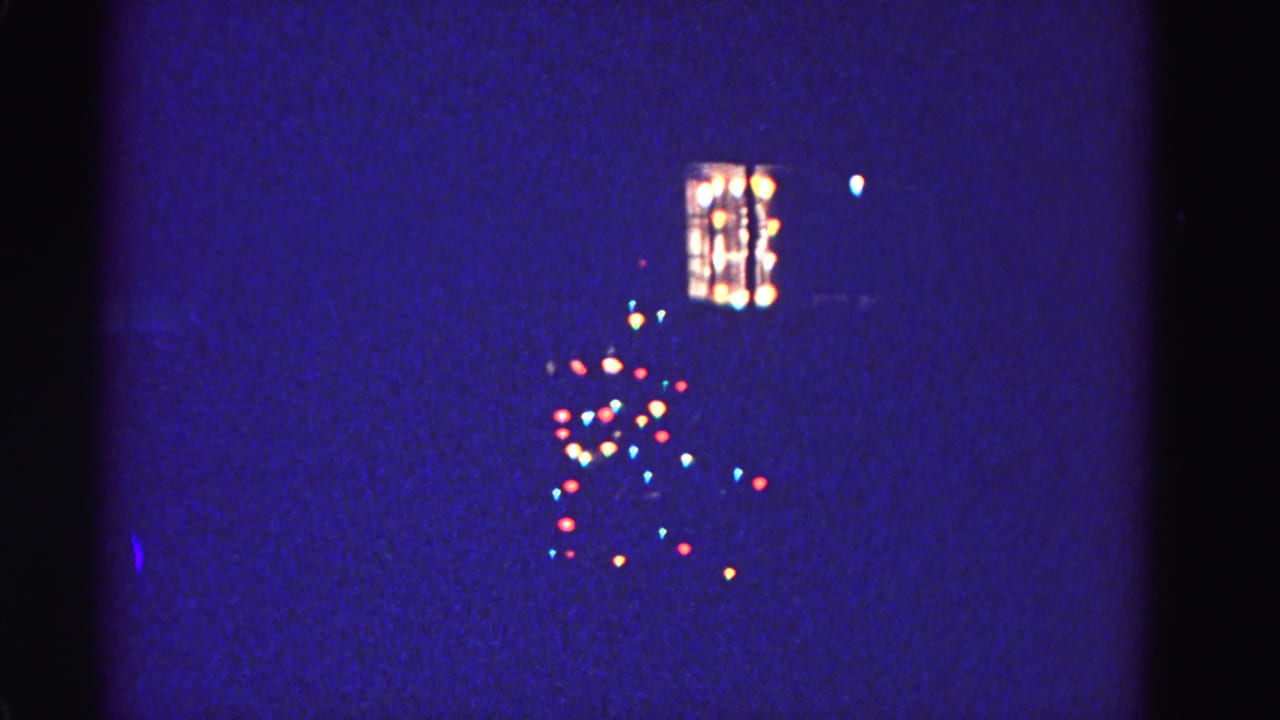 Multicolored incandescent Christmas light strings and illuminated window on a dark winter night, 8mm home movie, Hagerstown Maryland, circa 1962