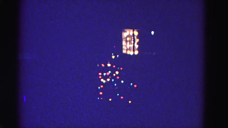 Multicolored incandescent Christmas light strings and illuminated window on a dark winter night, 8mm home movie, Hagerstown Maryland, circa 1962