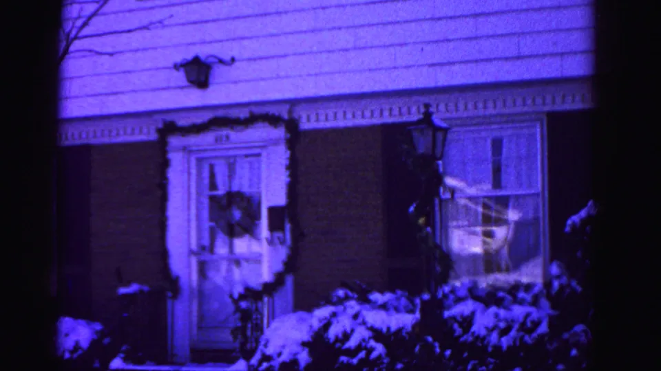 Decorated brick house facade with wreaths, garland, snow on shrubs, and wall lantern, 8mm film, Hagerstown Maryland, circa 1962