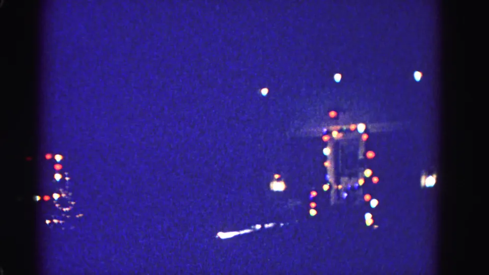 Out-of-focus multicolored Christmas lights bokeh against deep blue night sky, 8mm home movie, Hagerstown Maryland, 1962.