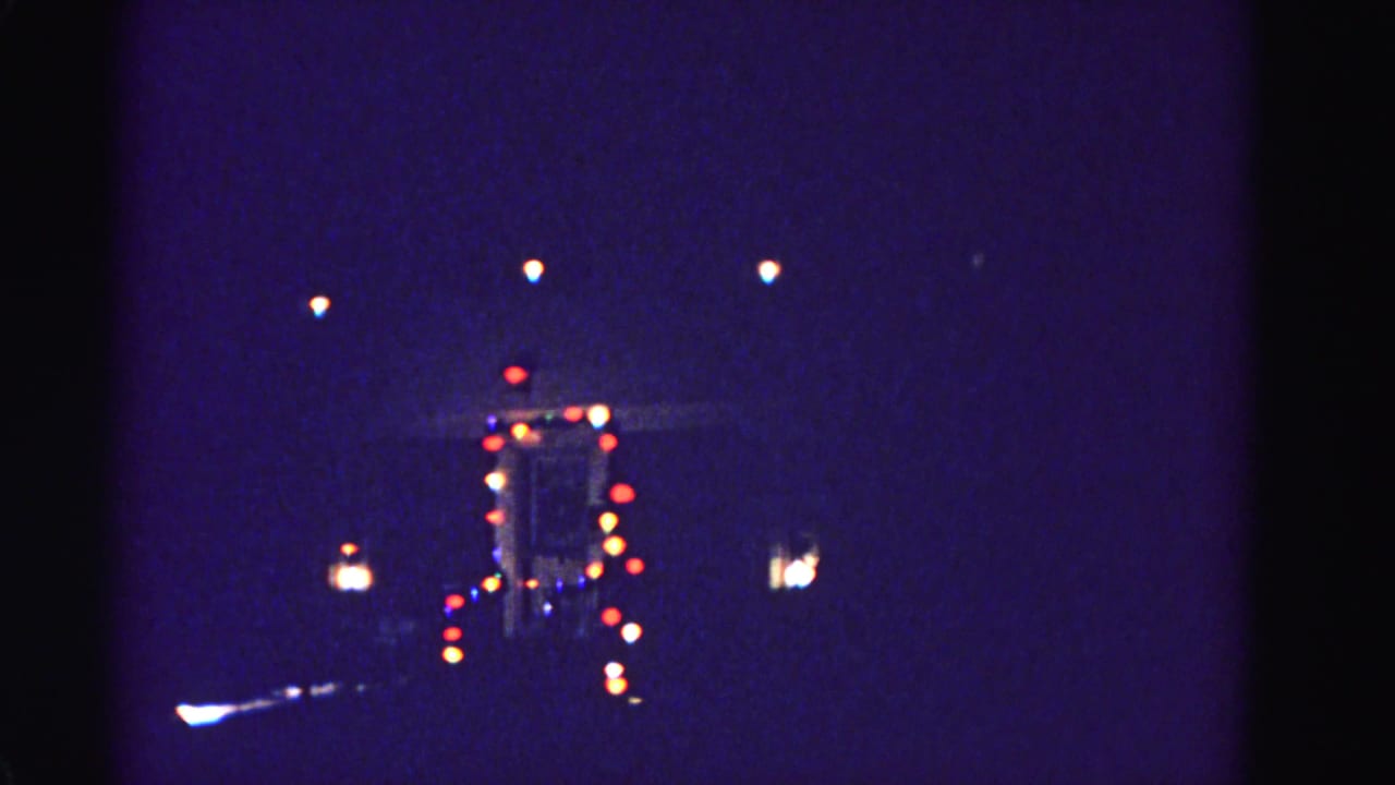 Slightly reframed view of the same distant lit building, with a partial illuminated element visible at the left edge of frame.