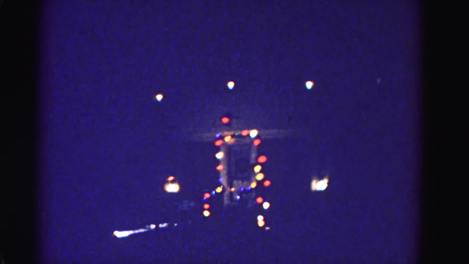 8mm home-movie frame circa 1962 of a festively lit building at night, attributed to Hagerstown, Maryland; horizontal light streak at lower frame suggests street or vehicle lighting.