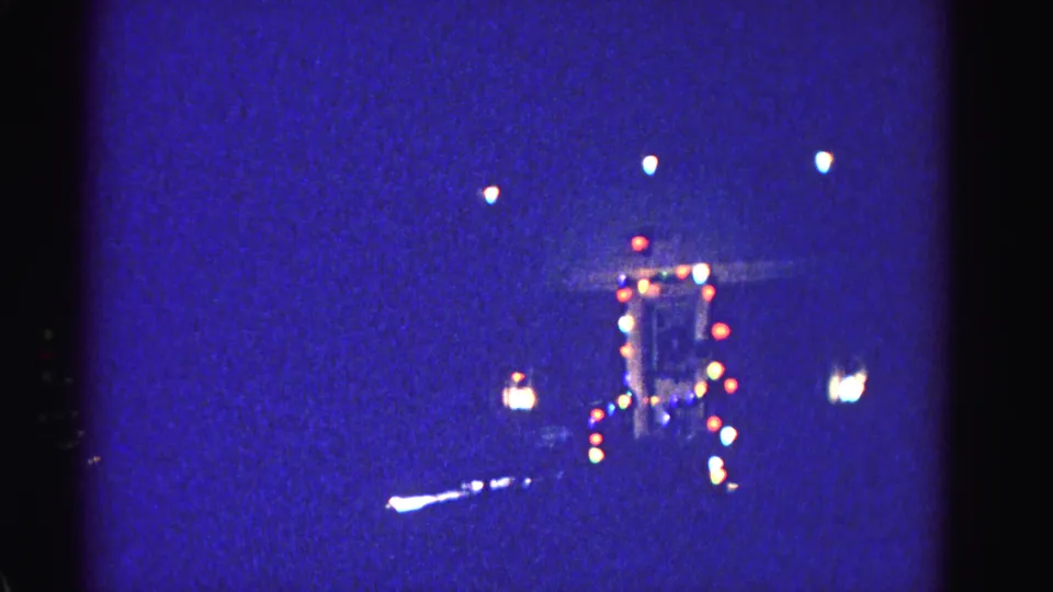 8mm home-movie final frame circa 1962 of a distant illuminated building at night, attributed to Hagerstown, Maryland; handheld framing consistent with prior frames.