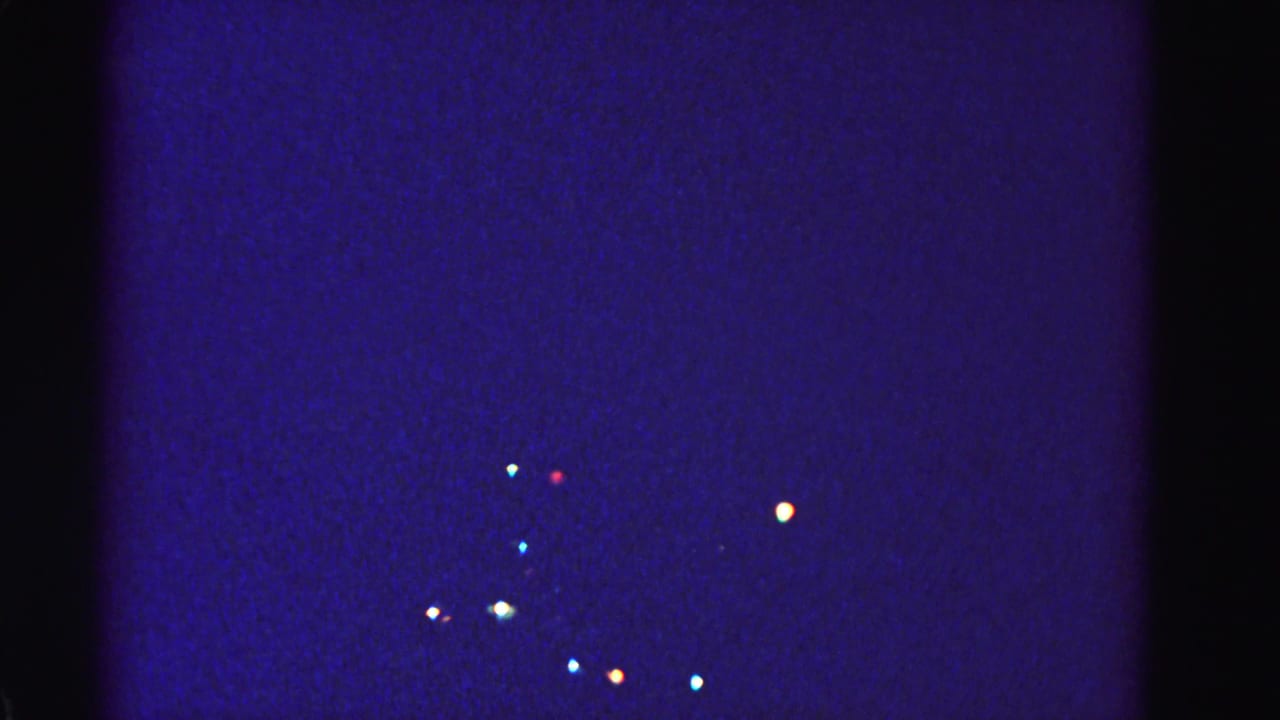 Opening frame of a 1962 8mm home movie showing distant Christmas lights glowing in a deep blue nighttime scene, Hagerstown, Maryland.