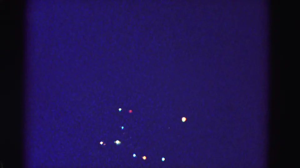 Opening frame of a 1962 8mm home movie showing distant Christmas lights glowing in a deep blue nighttime scene, Hagerstown, Maryland.