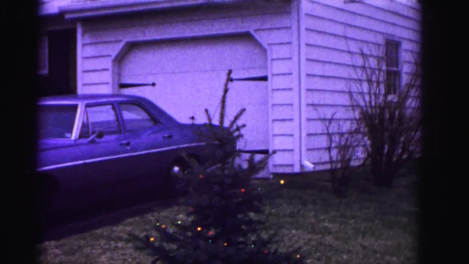 Driveway and garage of a suburban Hagerstown, Maryland home, 1962 — early-1960s full-size American sedan, white garage, and small Christmas tree with colored lights.