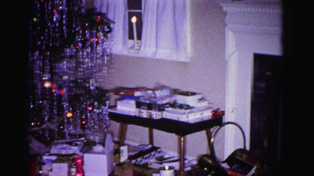8mm home movie frame from 1962 showing a tinsel-draped Christmas tree and gift-laden table in a domestic interior, Hagerstown, Maryland