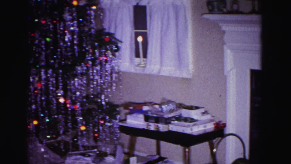 8mm home movie frame from 1962 showing more of the domestic interior including a white architectural element at left, Christmas tree with tinsel, and gifts, Hagerstown, Maryland
