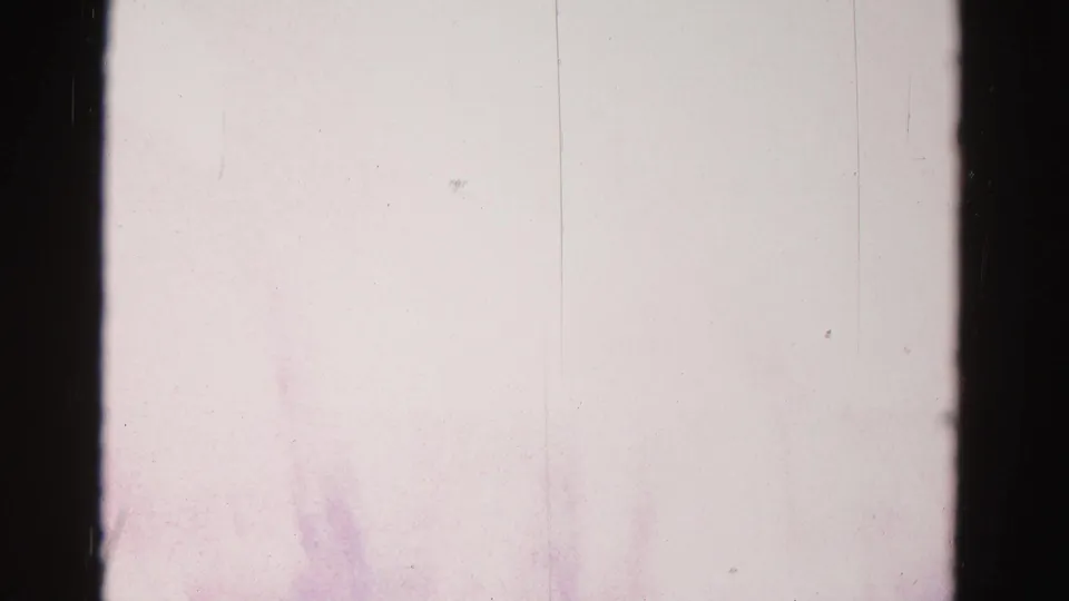 Near-white overexposed 8mm film frame, likely a reel splice or in-camera transition; faint silhouette visible at lower right corner.