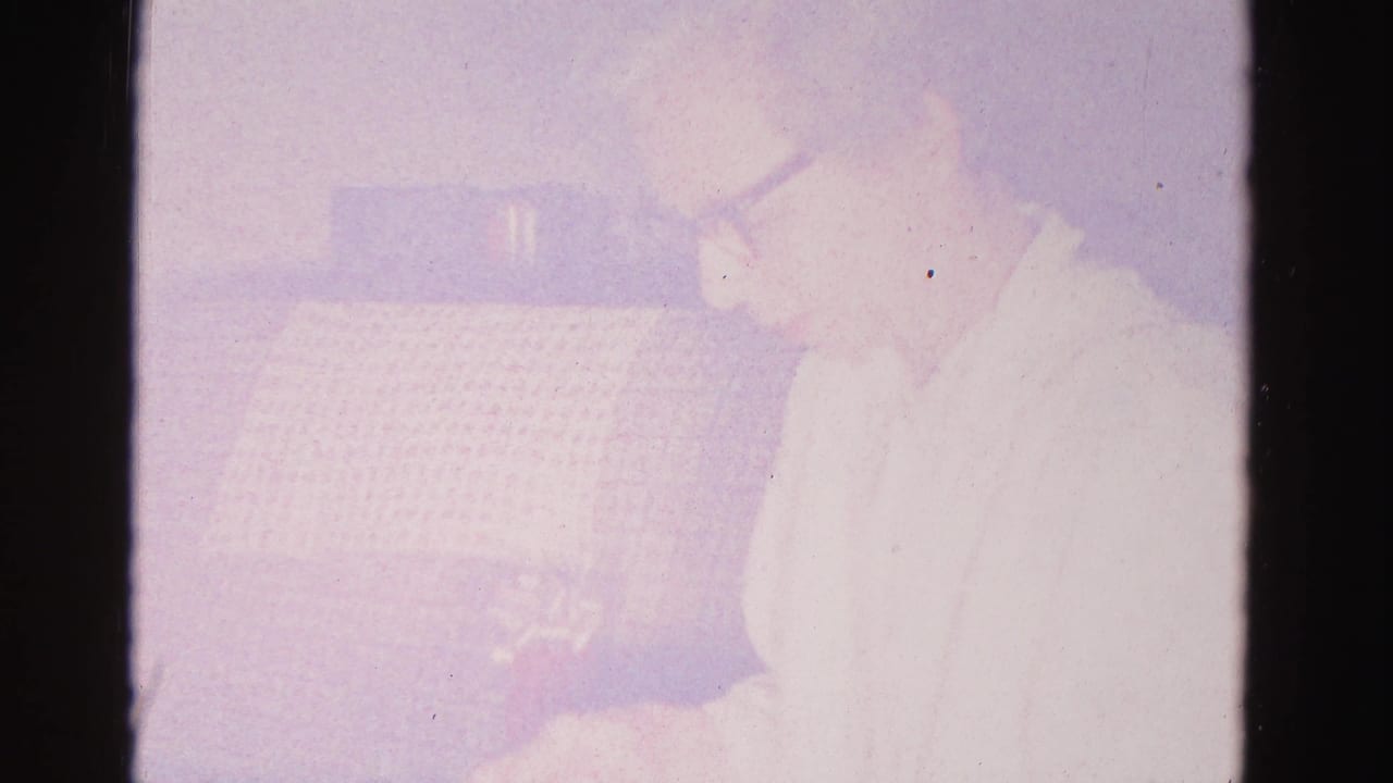 Severely overexposed frame; a woman is faintly visible against a bright wash, with patterned couch upholstery barely discernible.