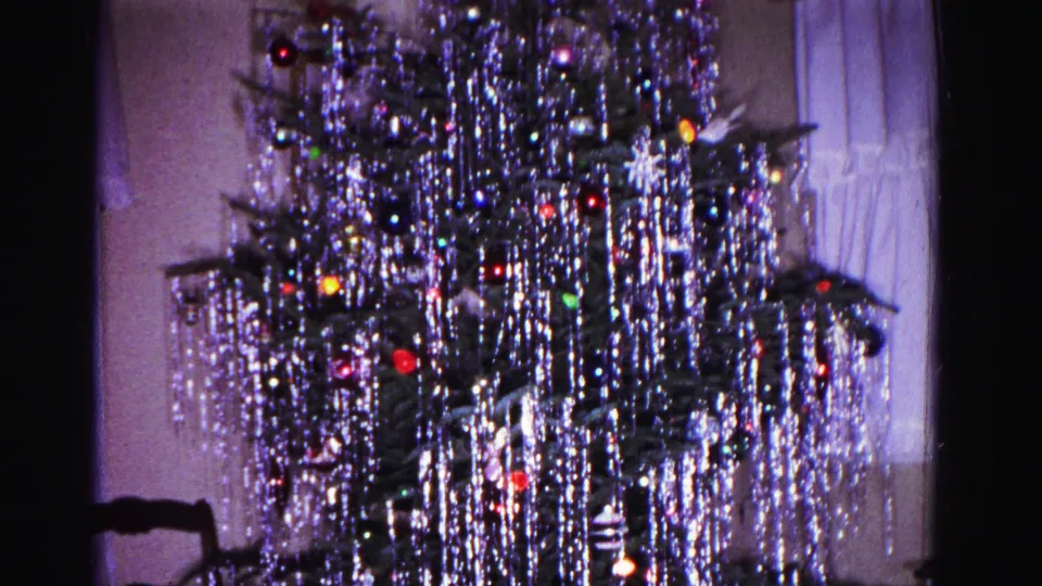 Lower portion of a tinsel-decorated Christmas tree in a 1962 domestic interior; sheer curtains and window visible in background, Hagerstown Maryland.