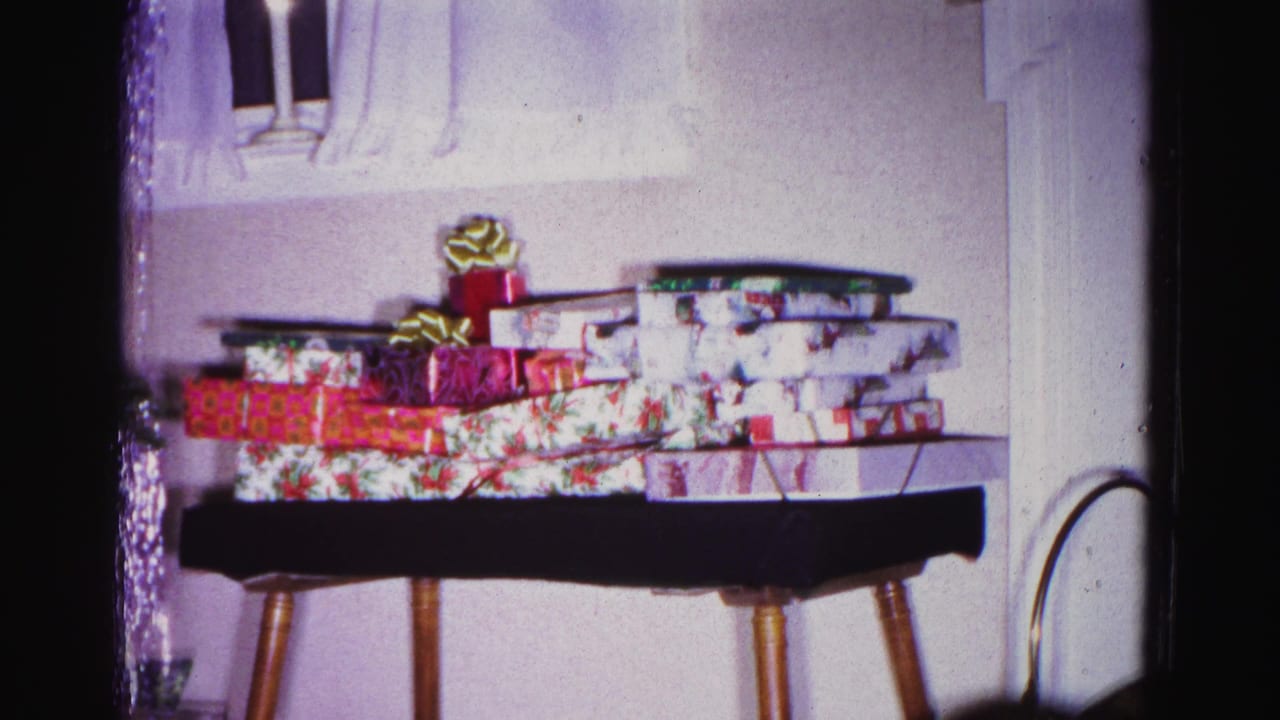 Wrapped Christmas gifts in floral and red patterned paper on a mid-century side table; from a 1962 home movie in Hagerstown, Maryland.