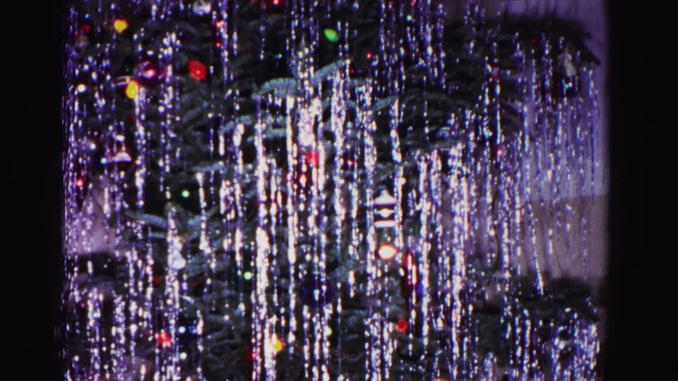 Christmas tree blanketed in silver tinsel and multicolored glass ornaments, from a 1962 8mm home movie in Hagerstown, Maryland.