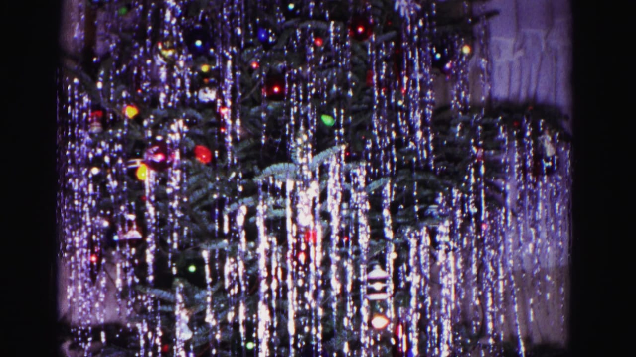Wide view of silver-tinseled Christmas tree with multicolored bulbs, from a 1962 8mm home movie in Hagerstown, Maryland.