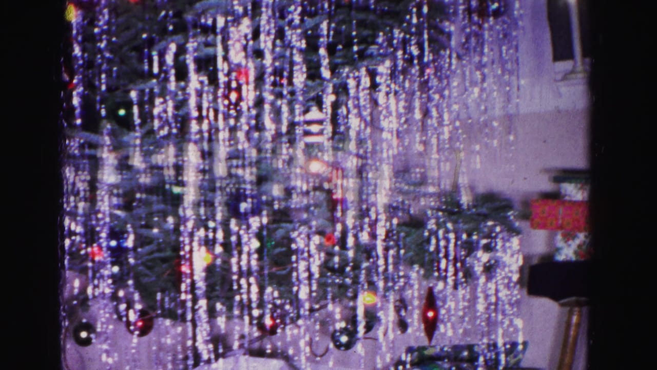8mm home movie frame, circa 1962, showing a Christmas tree densely covered in silver icicle tinsel with round ornaments; interior of a Hagerstown, Maryland home.