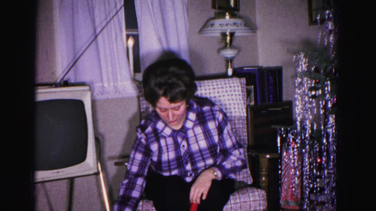 Young woman in plaid shirt beside a heavily tinseled Christmas tree; a boxy early-1960s television and table lamp are visible behind her, Hagerstown, Maryland, circa 1962.