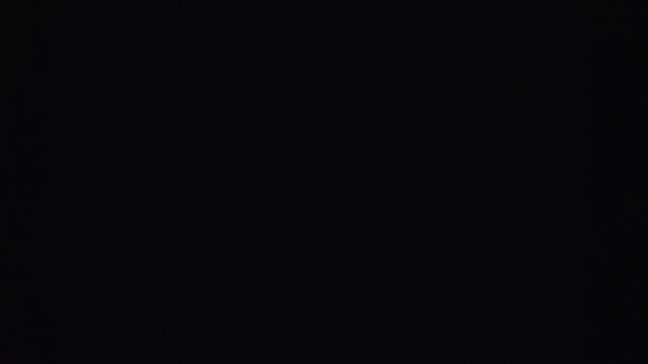 Heavily underexposed frame; faint silhouette of silver tinsel Christmas tree barely visible against darkness.