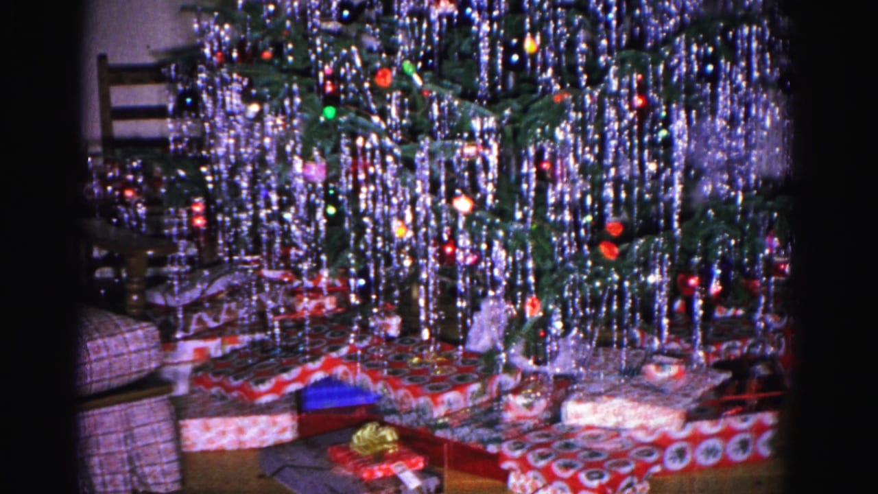 Wider shot of a silver-tinsel Christmas tree with wrapped gifts beneath it in a 1962 domestic interior, Hagerstown, Maryland.