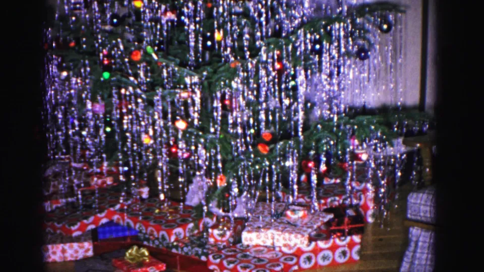 Silver-tinsel Christmas tree with wrapped presents at its base on a hardwood floor, 1962 home interior, Hagerstown, Maryland.