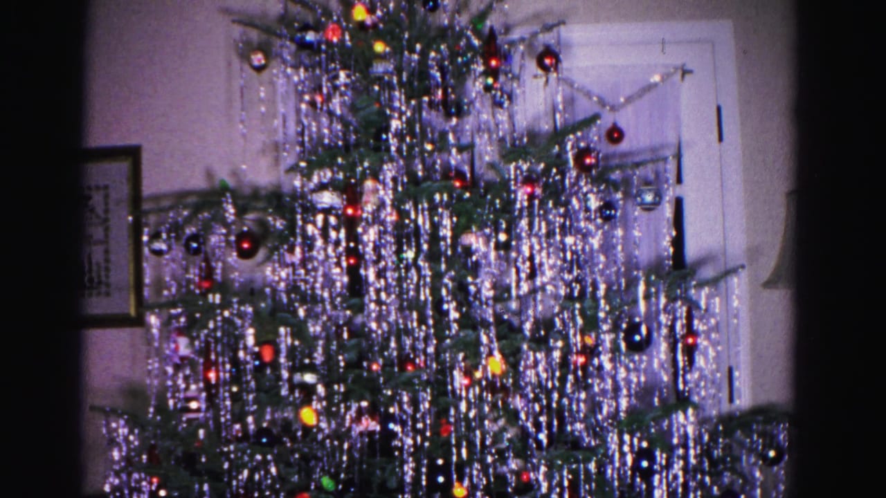 Pan across a tinsel-draped Christmas tree revealing a white interior door and framed wall artwork, from a 1962 home movie in Hagerstown, Maryland.