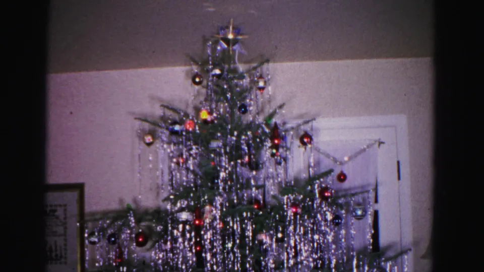 End of pan shot with Christmas tree shifted left, more of the domestic interior visible including door and wall, from a 1962 8mm home movie in Hagerstown, Maryland.