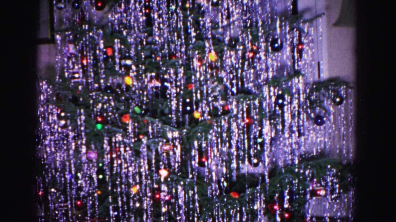 8mm home movie from 1962 showing a tinsel-heavy Christmas tree with red and mixed-color ornaments; pale wall background, Hagerstown, Maryland.