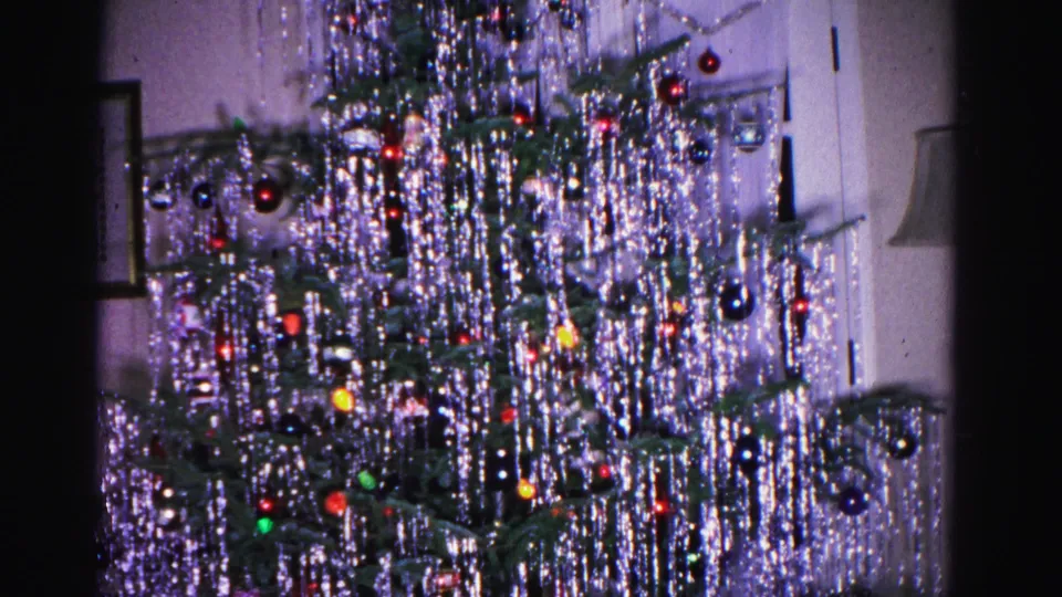 8mm home movie from 1962 showing a Christmas tree with silver tinsel and ornaments; a framed picture on the wall and interior door visible in domestic setting.