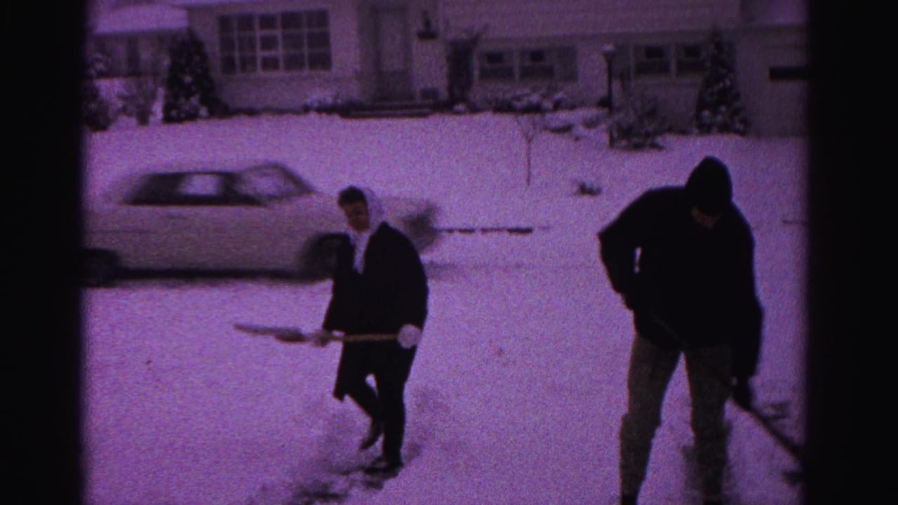 A man and a woman shovel snow near a parked early-1960s American sedan in what may be a Hagerstown, Maryland neighborhood, circa 1962.