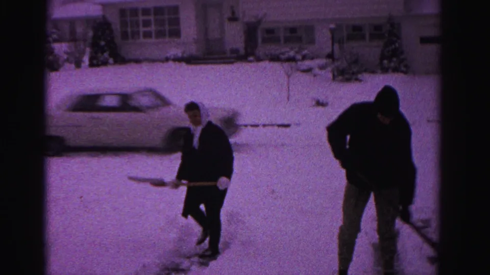 A man and a woman shovel snow near a parked early-1960s American sedan in what may be a Hagerstown, Maryland neighborhood, circa 1962.