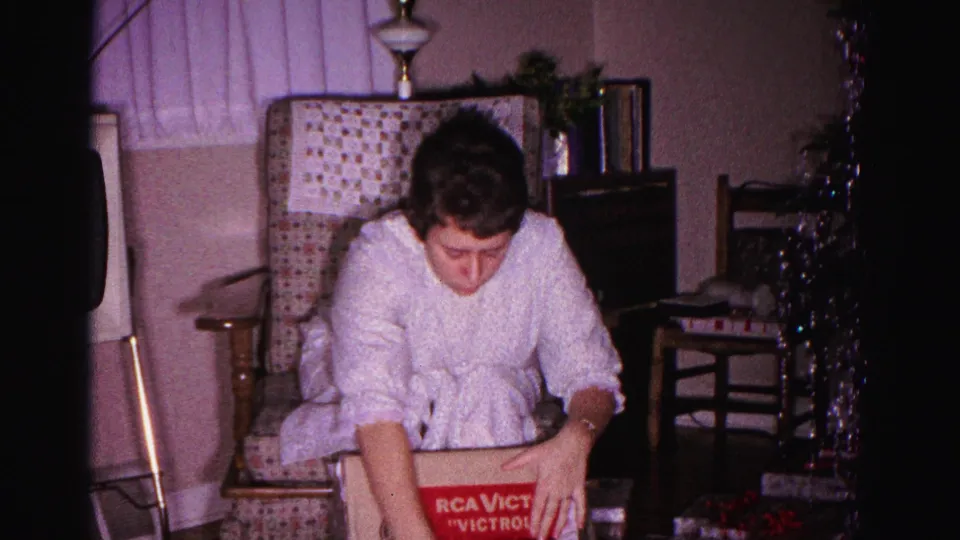 Woman opening a Christmas gift beside an RCA Victor Victrola box, domestic living room, Hagerstown Maryland, circa 1962, 8mm film.