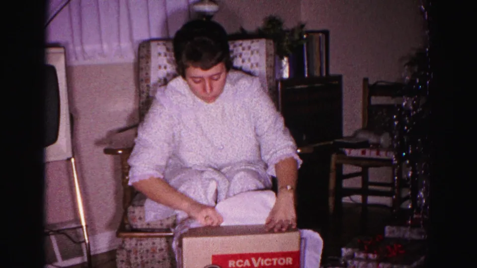 Woman looking into an RCA Victor Victrola gift box, domestic living room Christmas scene, Hagerstown Maryland, circa 1962, 8mm home movie.