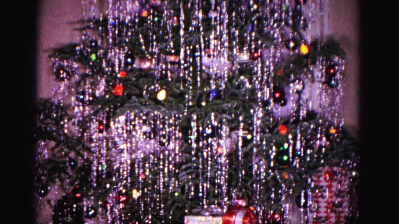 Decorated Christmas tree with silver tinsel, colored ornaments, lights, and wrapped gifts beneath it.
