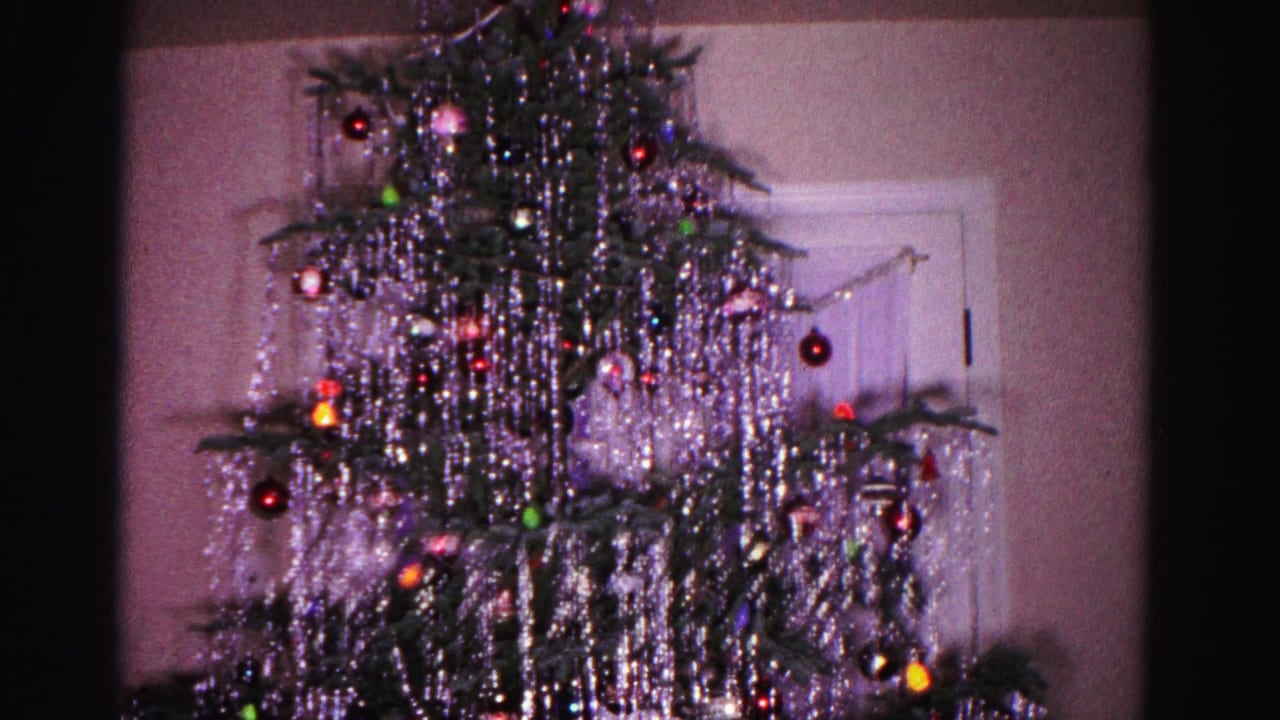 1962 Hagerstown Maryland home movie, Christmas tree with heavy silver tinsel, multicolored glass ornaments, and bulb lights in a domestic interior.