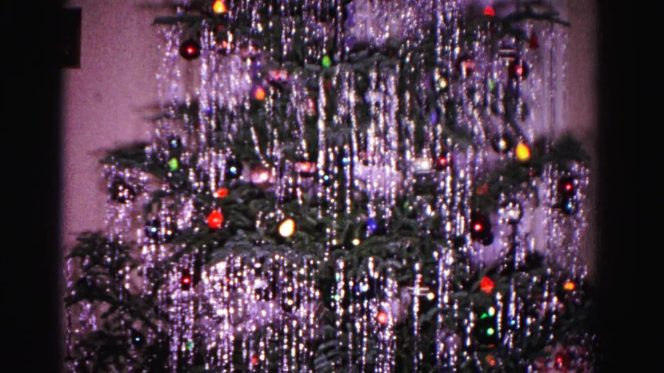 Closing frame of 1962 Hagerstown Christmas tree home movie, silver tinsel, colored glass ornaments, and multicolored lights on a real evergreen tree.