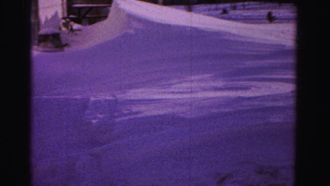 Close view of deep snow drifts with a building structure at right frame edge, strong purple tint throughout