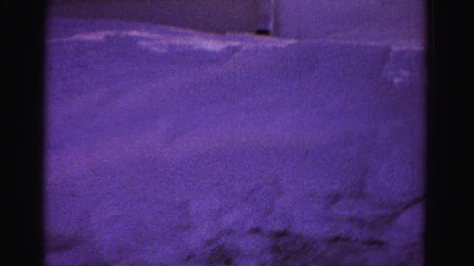 Purple-tinted 8mm frame of an uncleared residential snowfield with deep drifts filling the frame, circa 1962