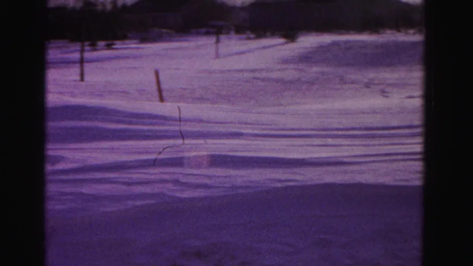 Final pan across open snowy residential landscape; wooden fence post and distant treeline visible; Hagerstown, Maryland area, circa 1962, 8mm home movie with purple dye shift.