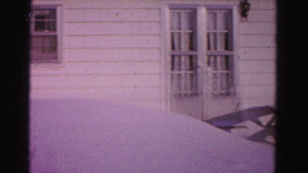 White clapboard house exterior with multi-pane door, windows, snow-covered yard, and partial picnic table; purple 8mm dye cast.